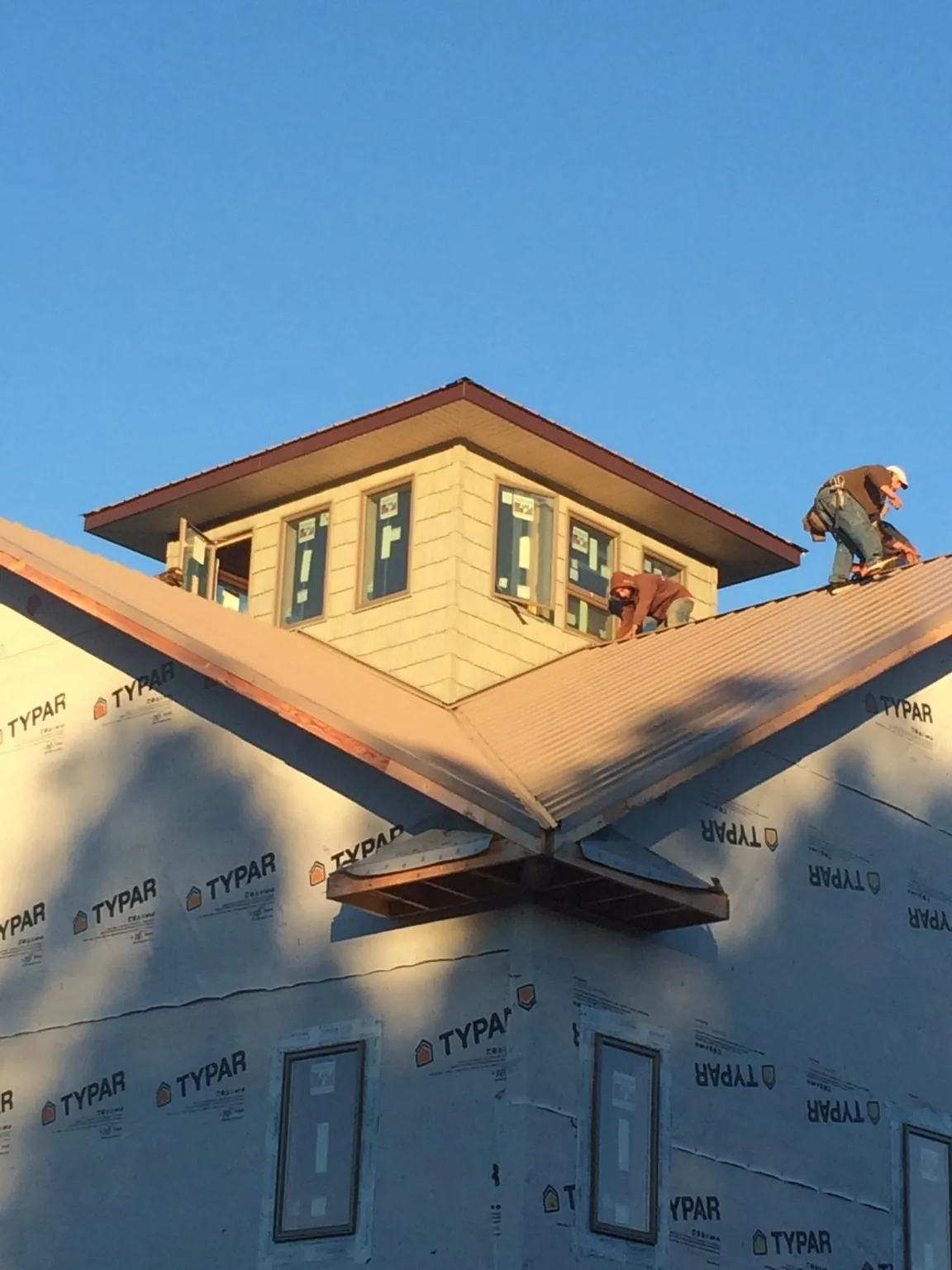 Roofers working around a rooftop cupola on a new metal roof at sunset — Roof Waterproofing in Dallas by Roofing Brothers